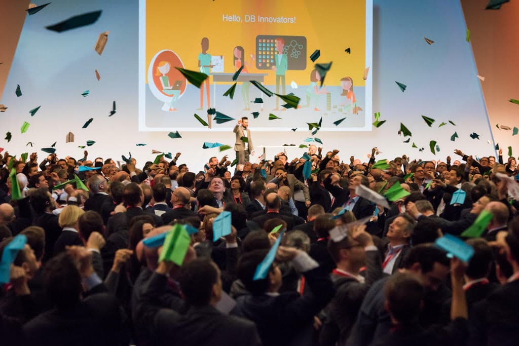 A hall of participants throwing paper planes during Frederik's keynote