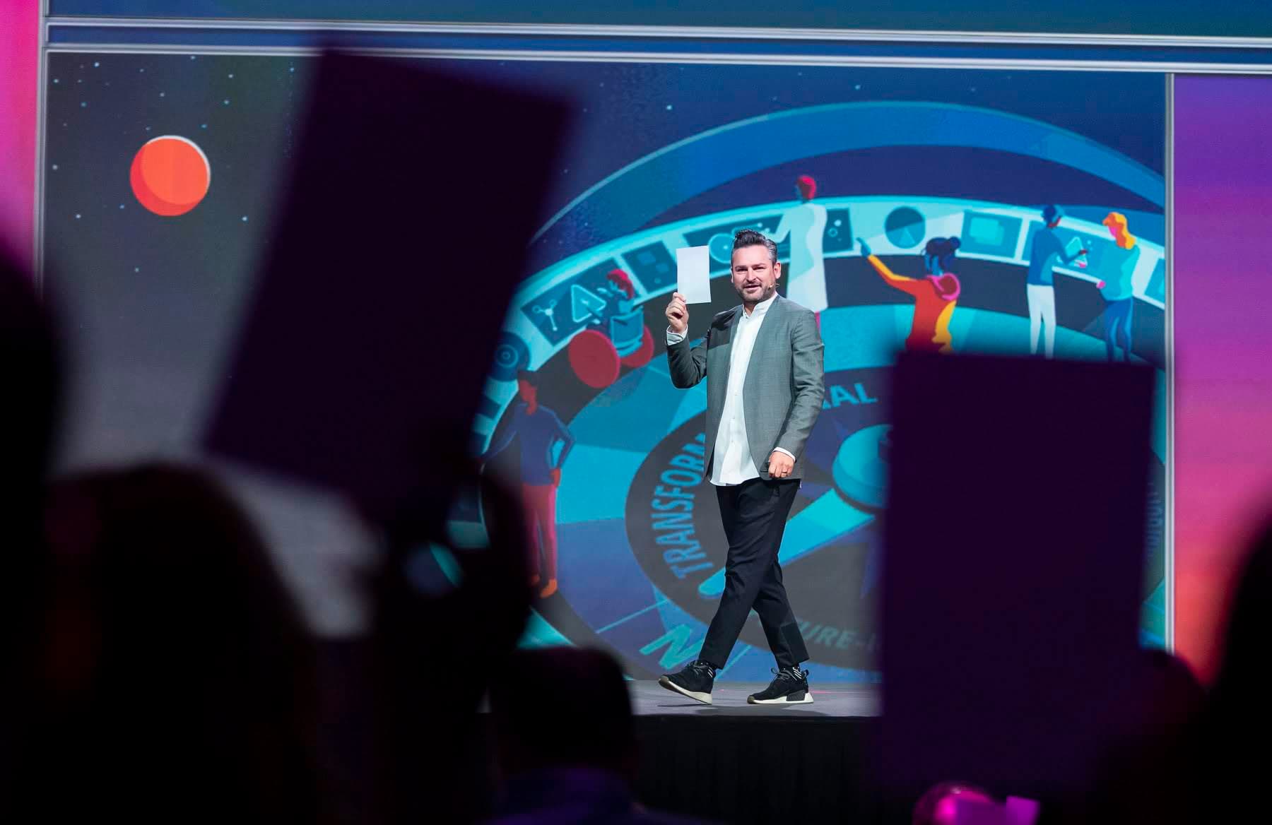 Dr. Frederik G. Pferdt walking mid-stage, framed by the audience